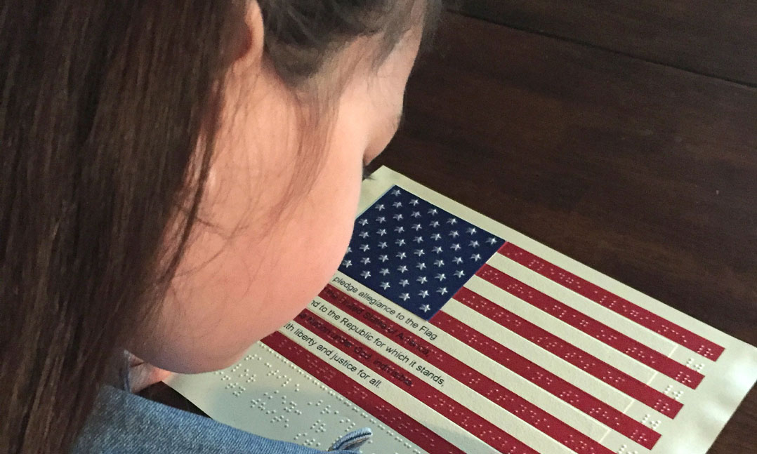 A child explores a Braille version of the U.S. flag