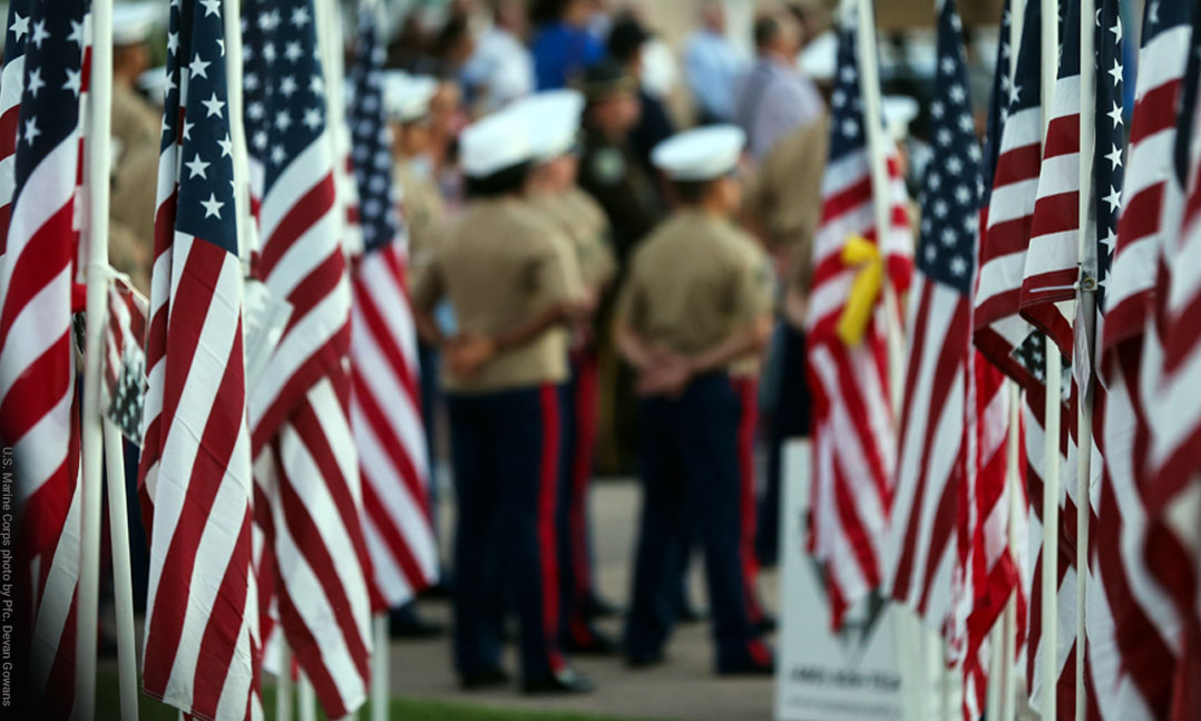 Marines in dress uniform stand at attention surrounded by US flags