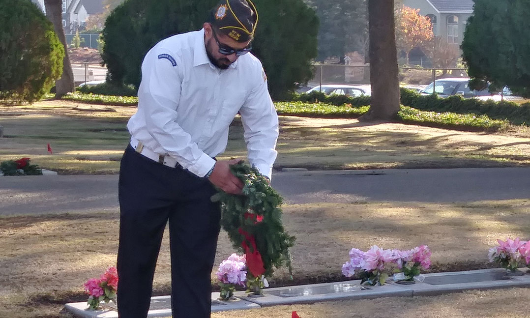 A VFW member prepares a wreath for a veteran's grave during Wreaths Across America