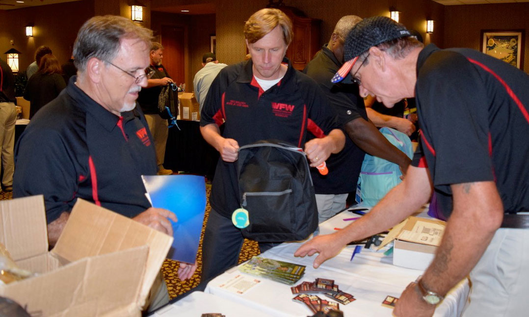 VFW members look over resource materials available for homeless veterans while packing rucksacks for veterans outreach events