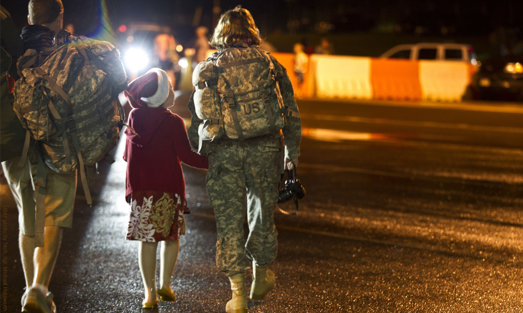 Man carries his wife's bags while young girl gets reacquainted with her mom who returned from Iraq deployment