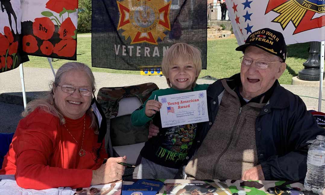 VFW Post 10904 member Ed Reader (far right) presents a child with a Young American Award during a community event in Manchester, Tenn., earlier this fall. At 97, Reader remains quite active in his Post and enjoys working with the local youth. 