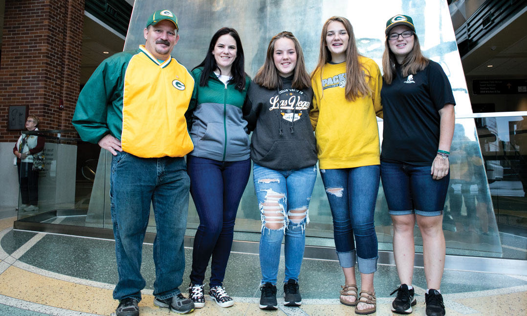 Military veteran stands next to his wife and three daughters