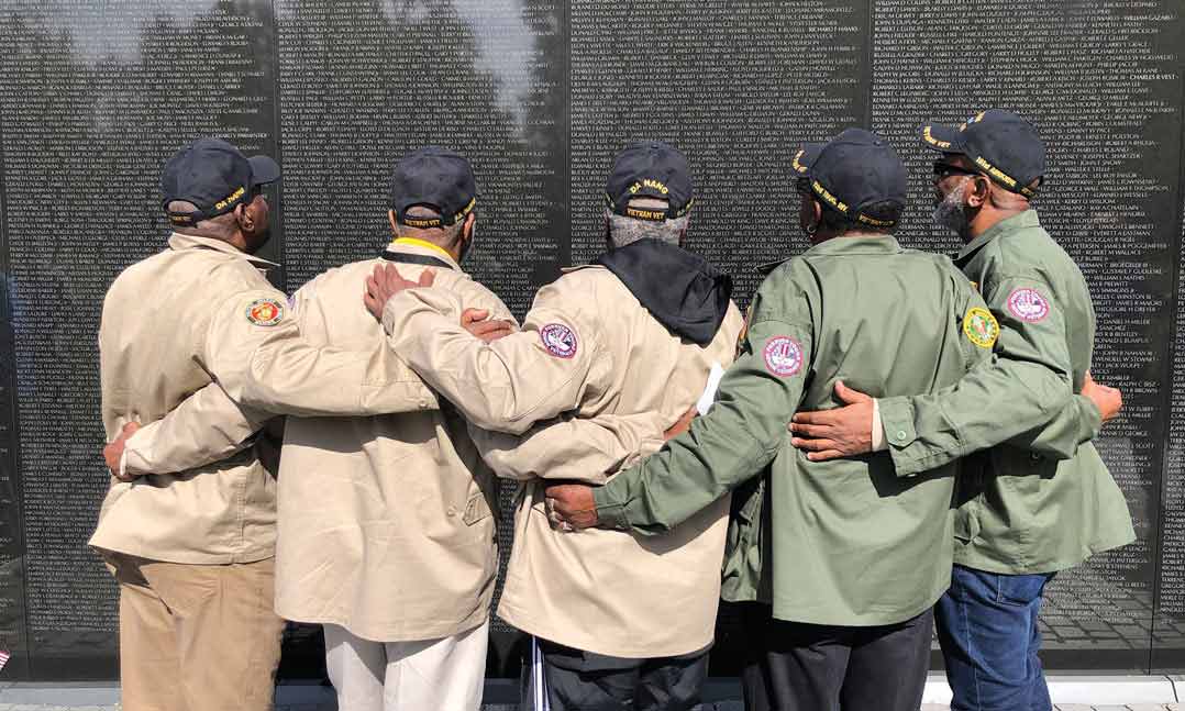 Five brothers who all served in Vietnam embrace in front of the Vietnam Veterans Memorial at the National Mall