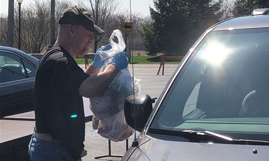 A VFW member hands out a free bag of food to a local family during COVID-19