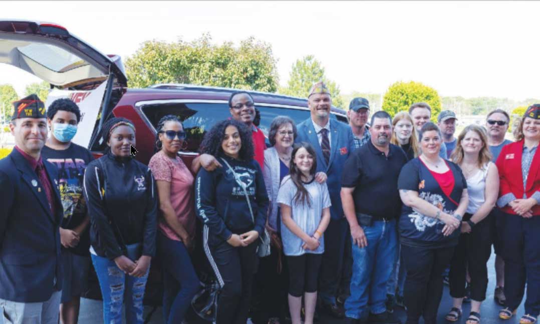 VFW members join the wife of a late veteran to present keys to a wheelchair-accessible van to a wounded veteran