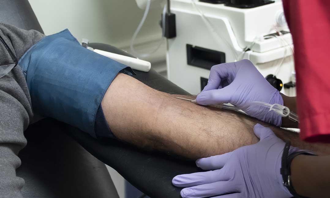 Nurse inserts a needle into a donors arm for a blood donation