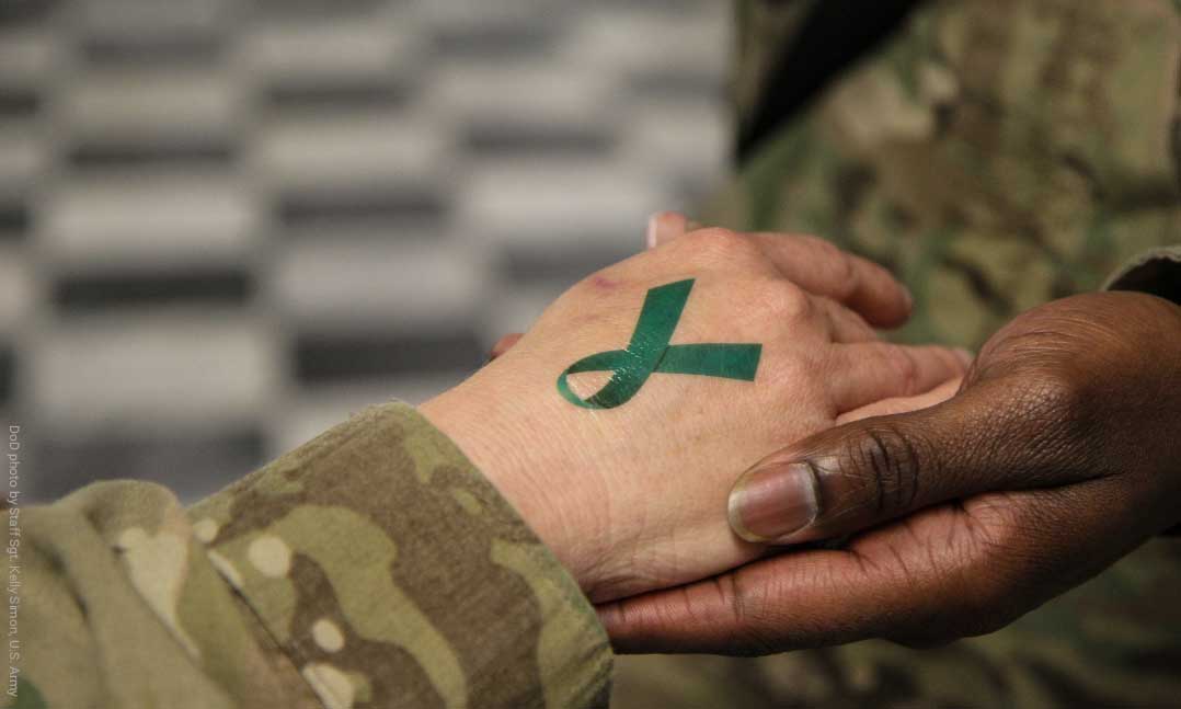 Soldier's hand holding a soldier's hand displaying a temporary teal ribbon tattoo DOD photo by Staff Sgt. Kelly Simon, U.S. Army