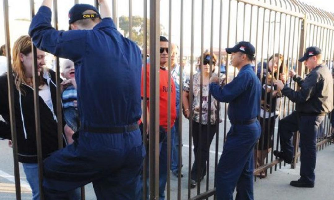 Military families speak between a metal barrier