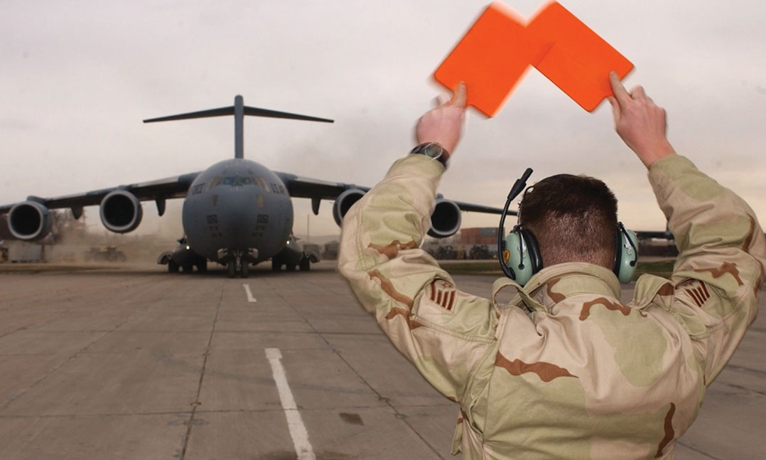 Service member waves orange flags at airplane