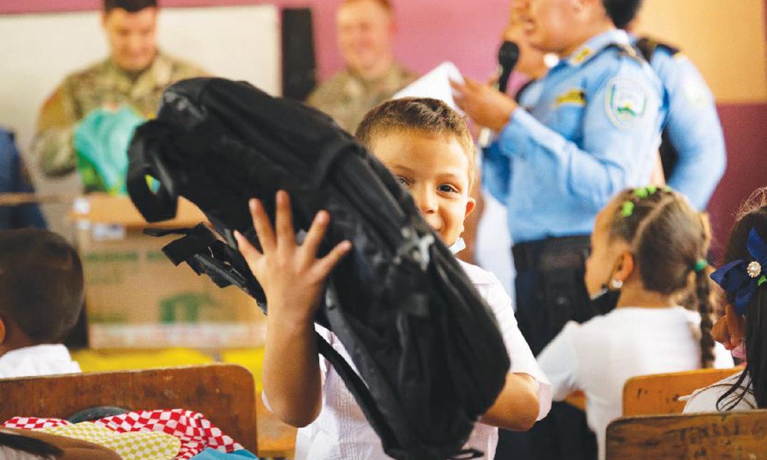 A student at Escuela Roberto Mejia Castillo School in La Paz, Honduras, grins as he receives a backpack from soldiers.