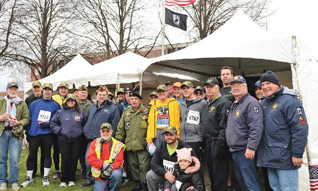 Members of VFW Post 2046 and other veterans stand together at the Veterans’ Row area before the 87th annual Manchester Road Race