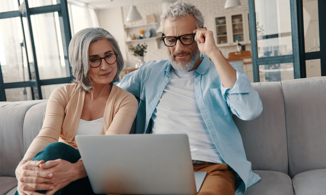 Elderly couple sits at a computer