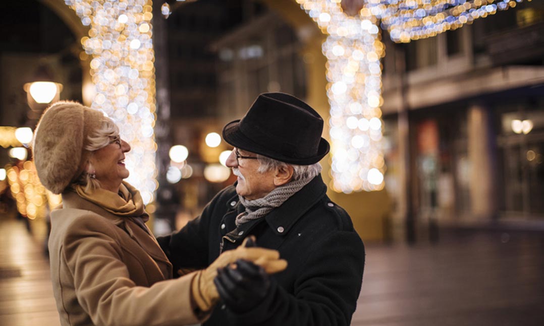 Older couple dancing in front of holiday lights