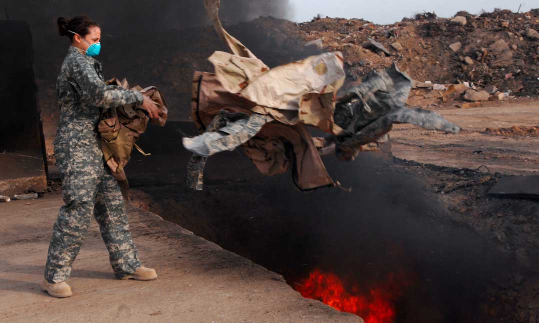 Service member throwing trash into a burn pit