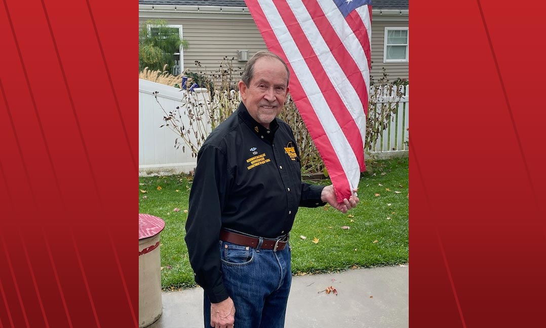 Vietnam veteran Norman Machelor standing by the US flag