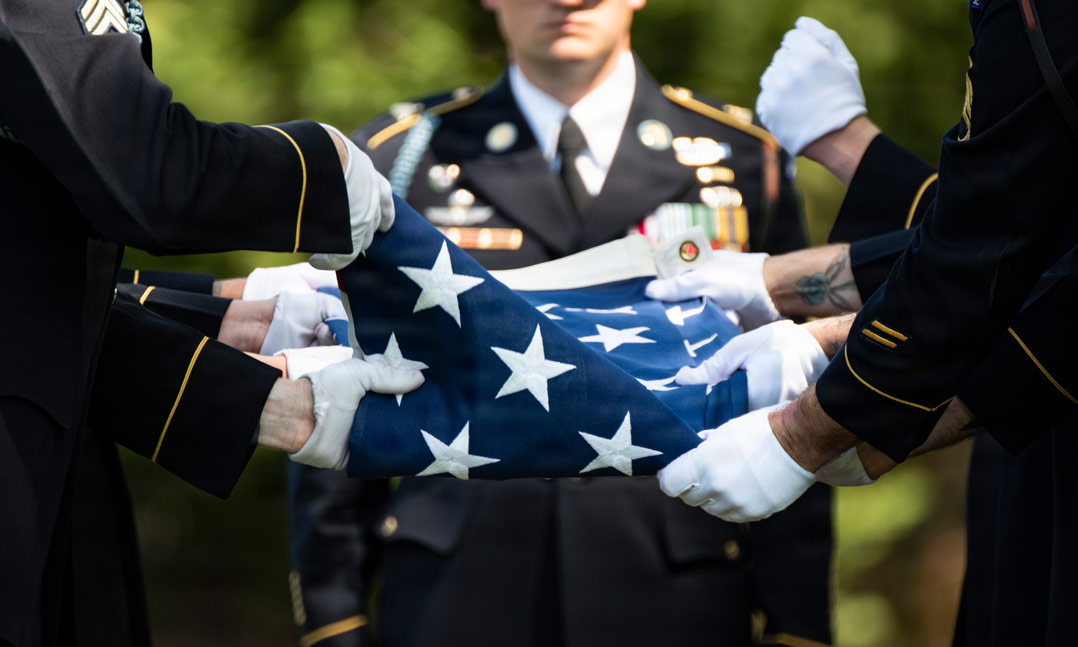 military members fold a flag during a veteran burial